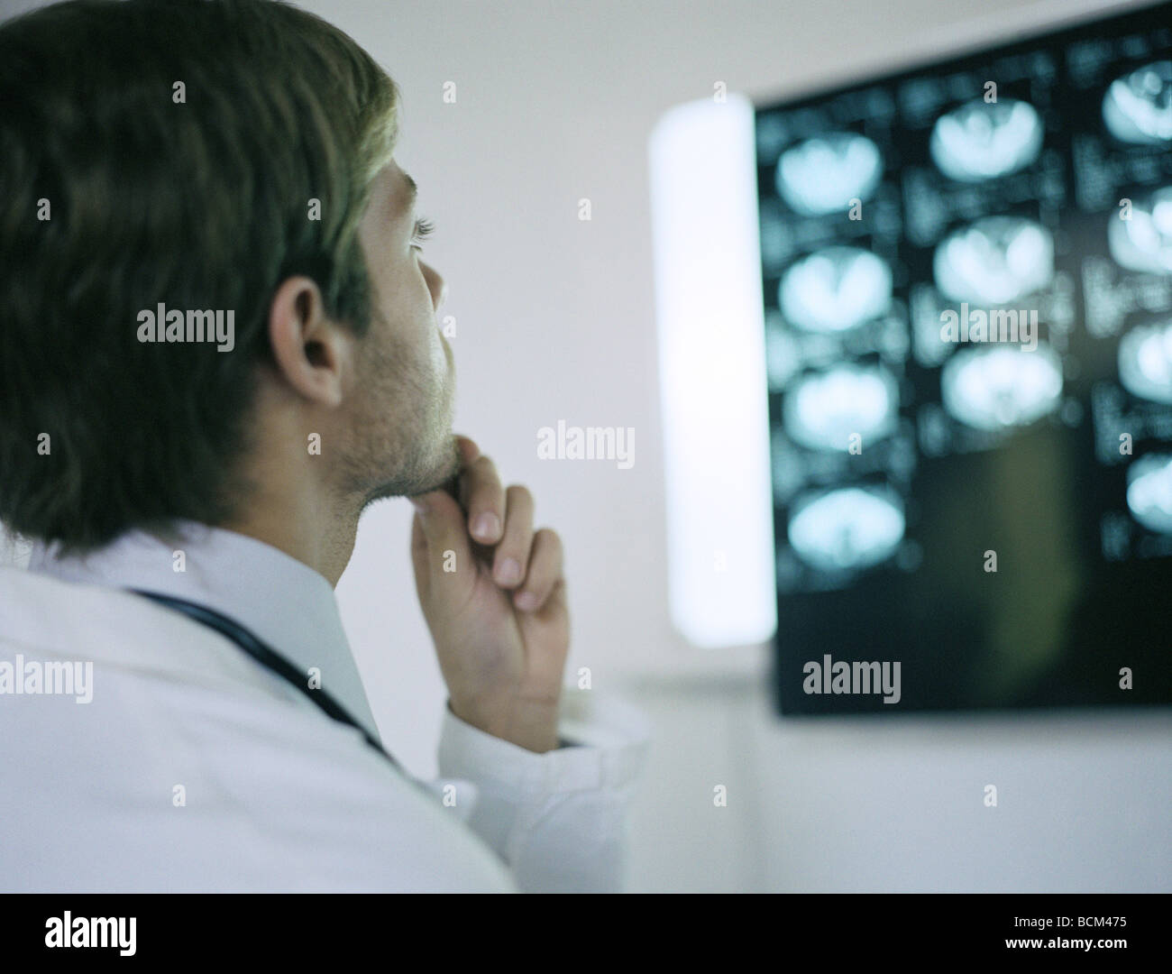 Doctor looking at MRI scans, hand under chin Stock Photo