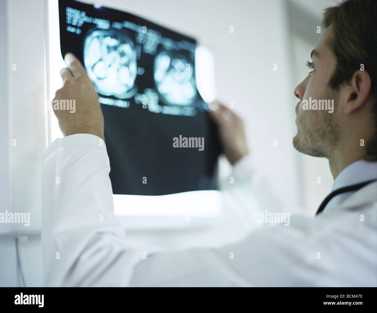 Doctor holding up and examining MRI images, rear view Stock Photo