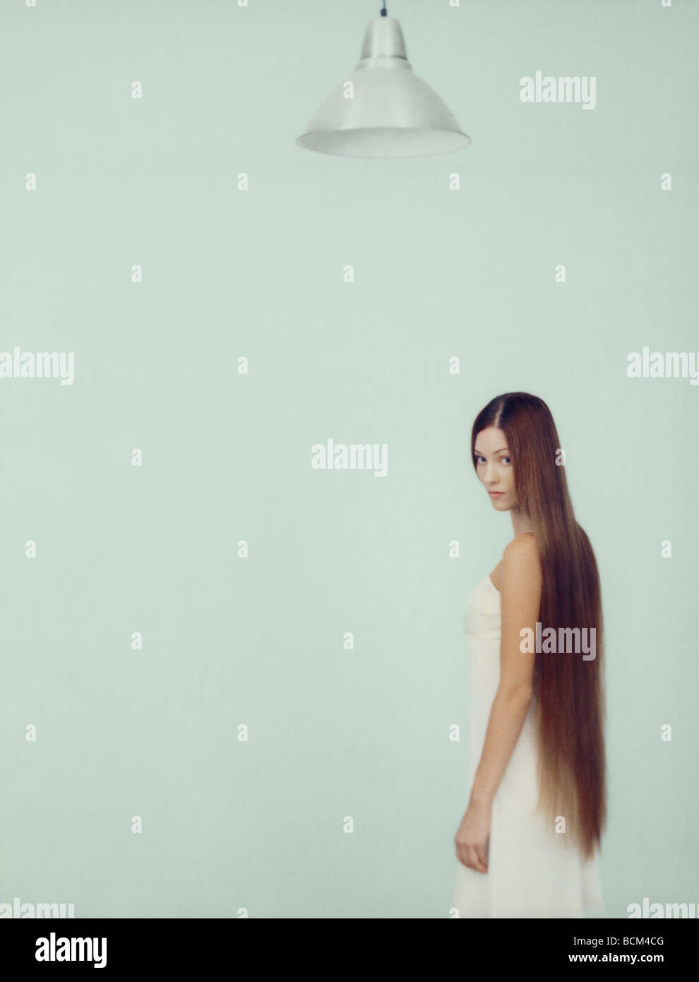 Young woman with long hair, looking over shoulder at camera Stock Photo