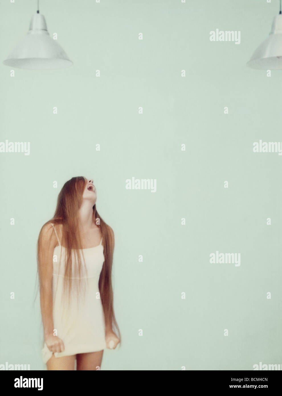 Young woman screaming, holding edge of dress Stock Photo
