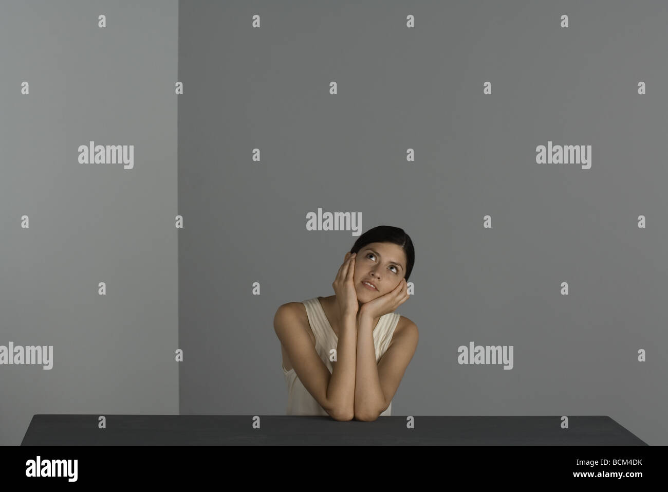 Woman sitting with chin in hands, looking up, smiling Stock Photo - Alamy