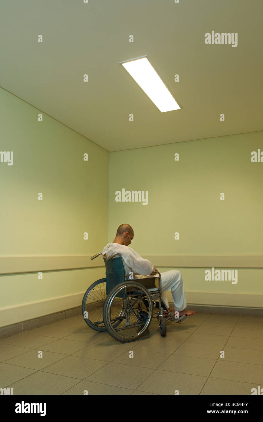 Male patient sitting in wheelchair, head down Stock Photo