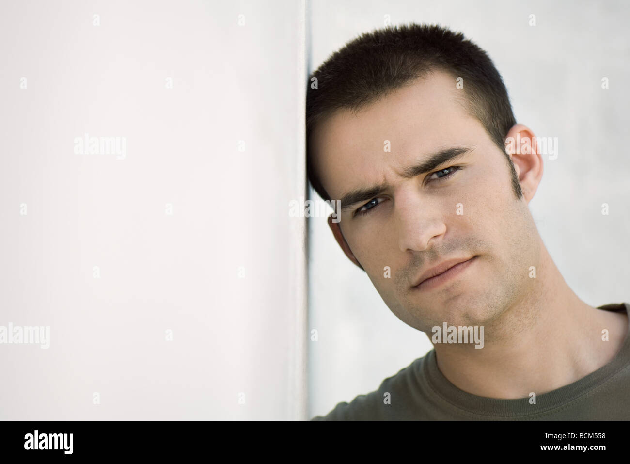 Man leaning head against wall, furrowing brow Stock Photo - Alamy