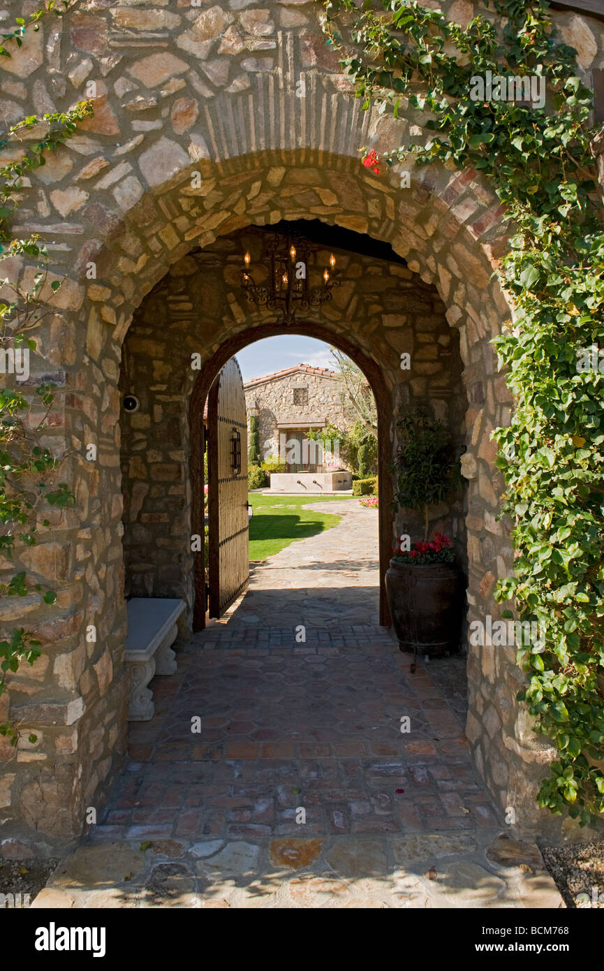 Arched stone entry way leads to through open wooden door Stock Photo