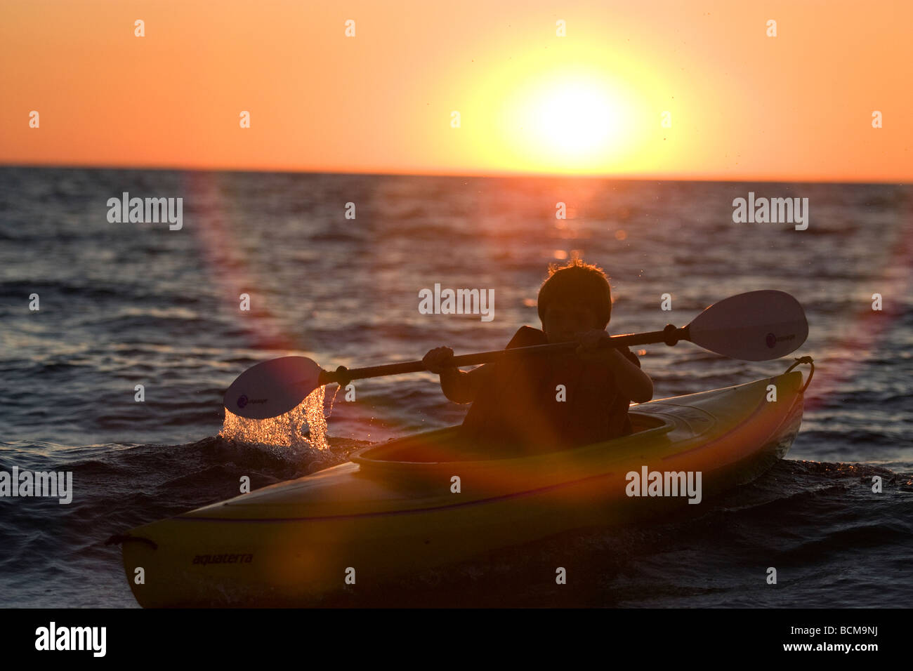 Young boy kayaking at sunset Stock Photo
