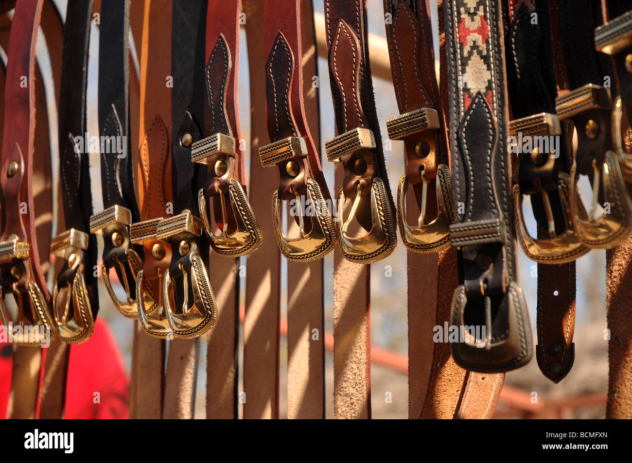 Leather belts with golden buckles displayed for sale at a local market in the north of Argentina Stock Photo