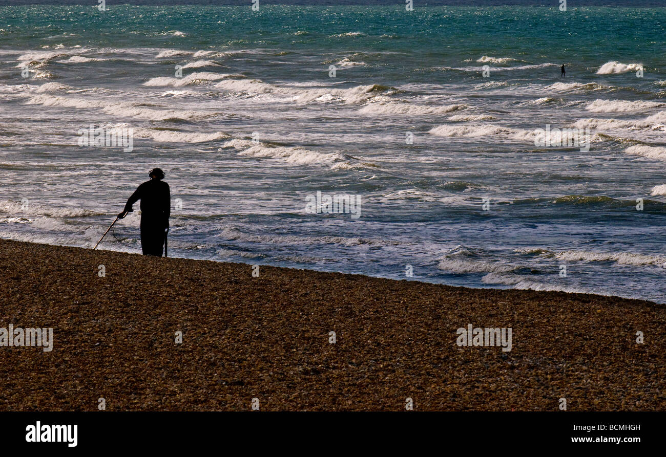 A metal detector searching on the shingle beach at Brighton in Sussex