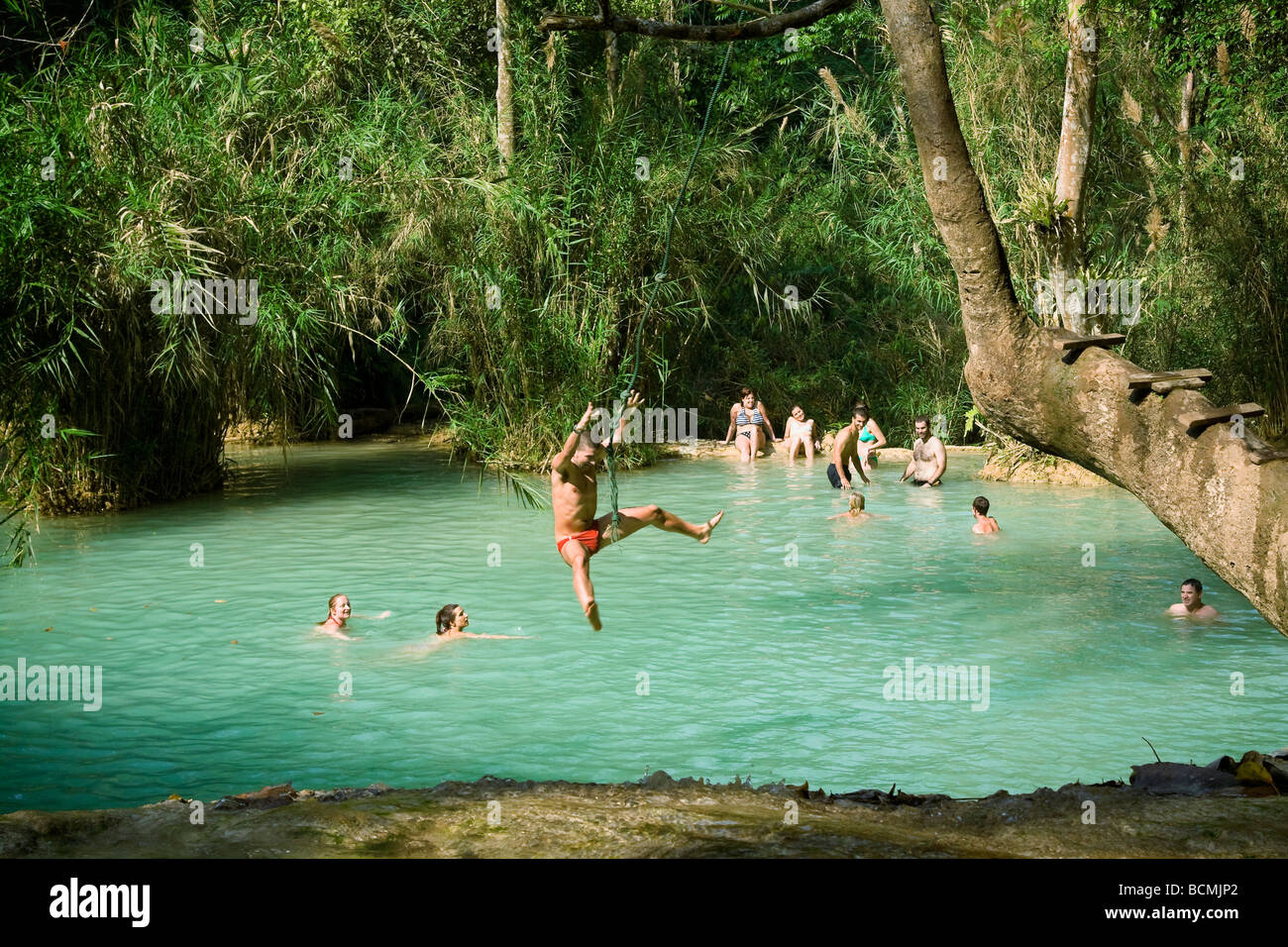 Tourists and locals swim and relax in pond at Tat Kuang Si waterfall  near Luang Prabang in Laos Stock Photo