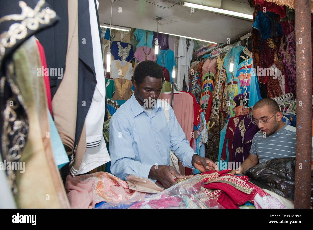 A shopkeeper shows traditional Tunisian clothing to a tourist from the United States in the Medina (old city) in Tunis. Stock Photo