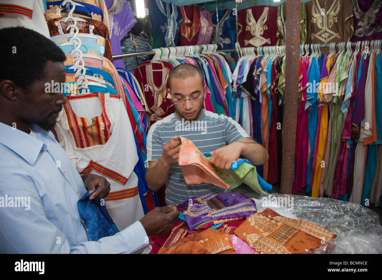 A shopkeeper shows traditional Tunisian clothing to a tourist from the United States in the Medina (old city) in Tunis. Stock Photo