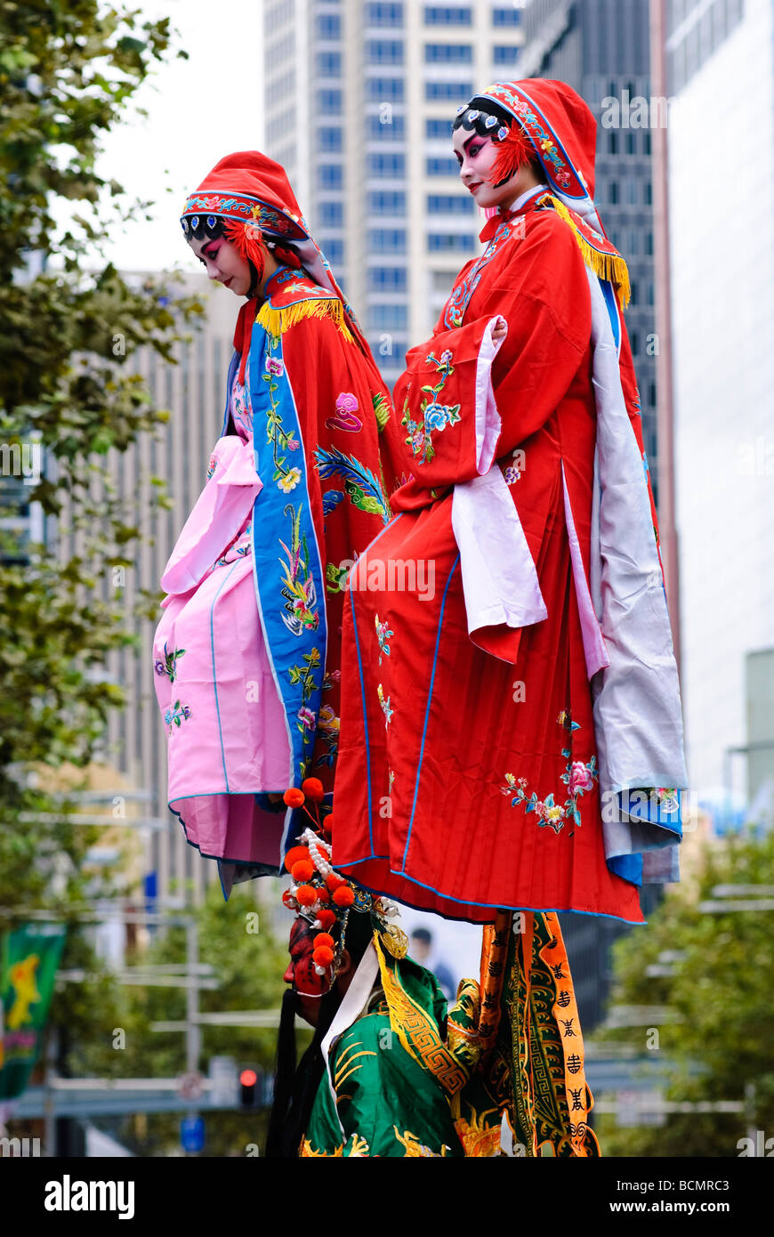Two young Chinese women in colourful traditional costume, being carried during a Chinese New Year parade. Stock Photo