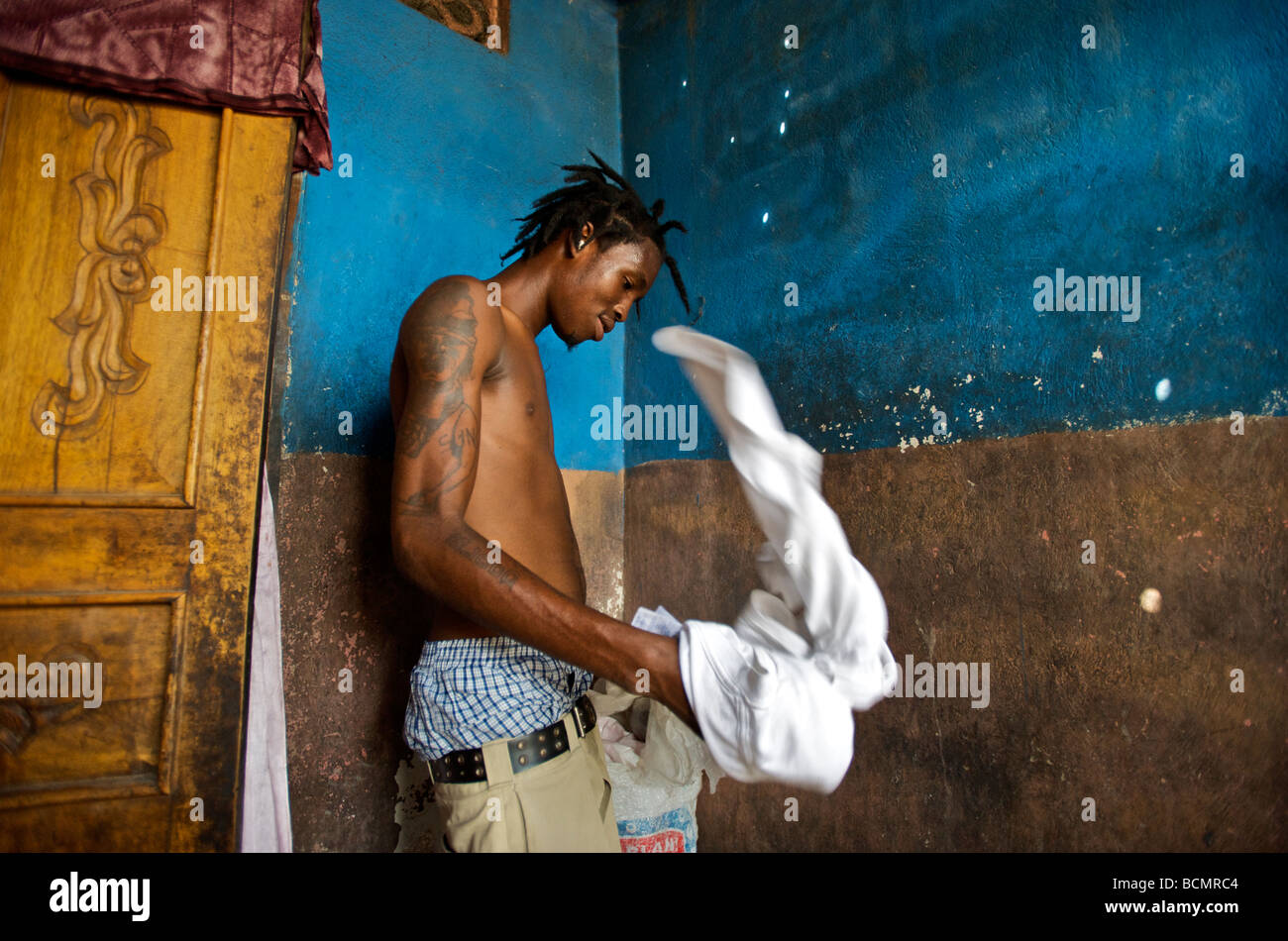 Rapper 2Double changes shirts in his 2-room home in Cite Soleil in Port ...