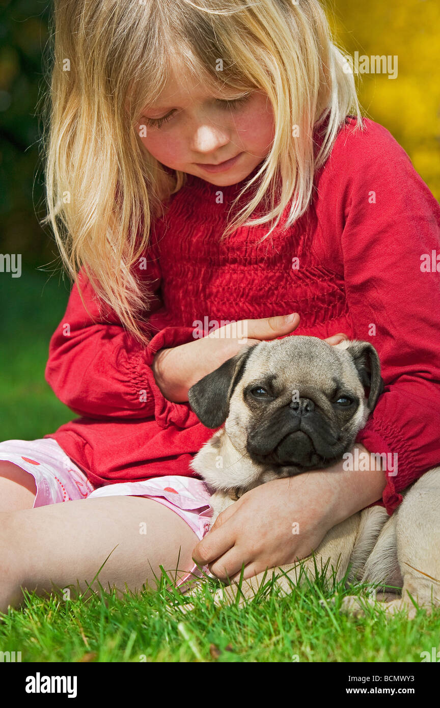small girl with pug dog puppy sitting on meadow Stock Photo Alamy