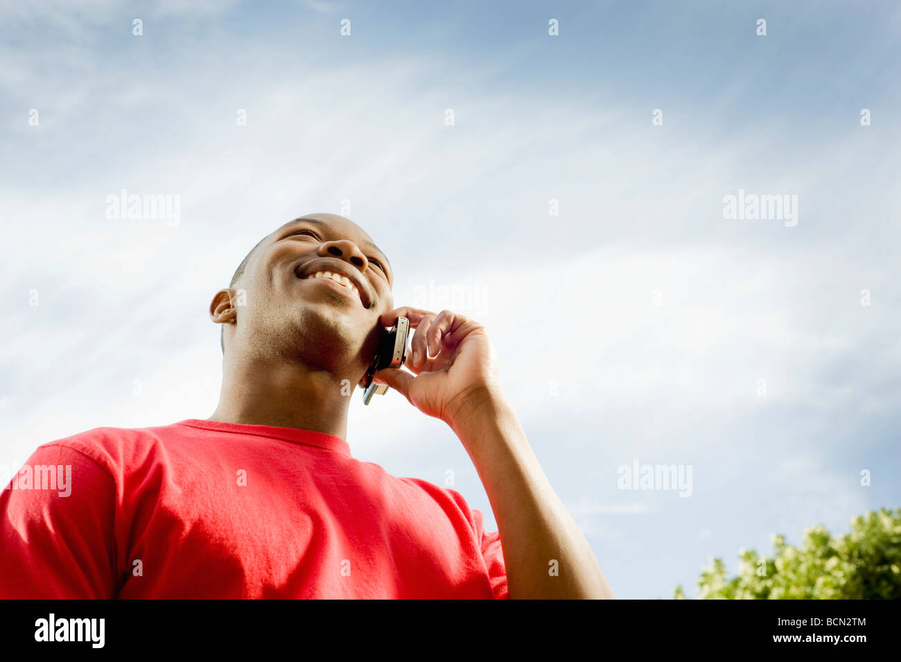 A young man on a cellular phone, shot from below Stock Photo