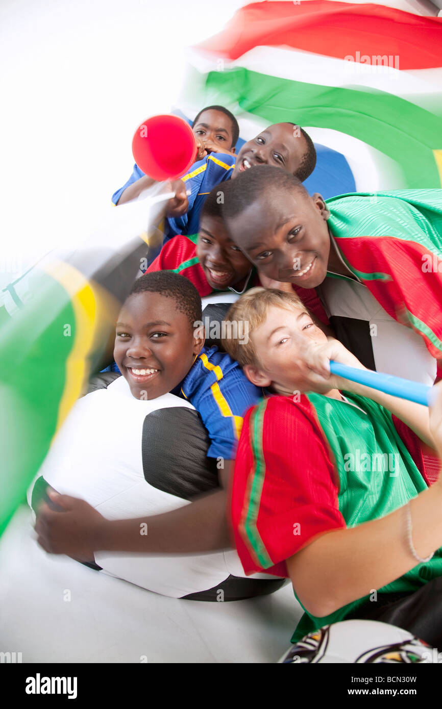 A playful group of young mixed race boys in soccer supporters kit with