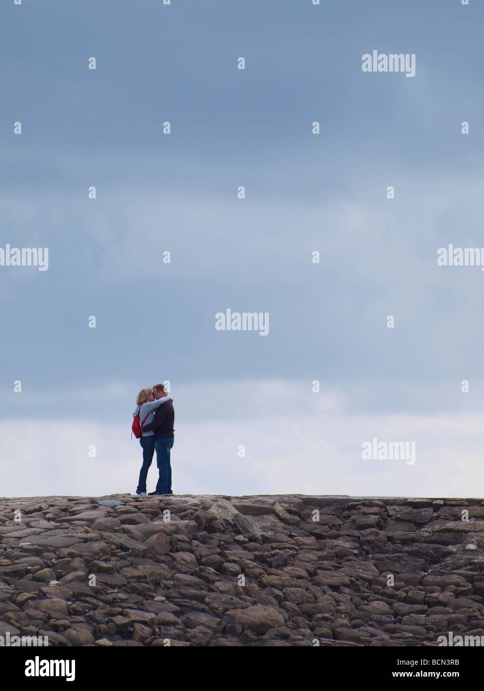 Middle aged couple standing on breakwater kissing Stock Photo