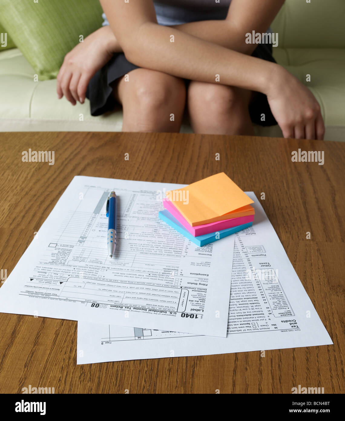 Woman on Sofa and Tax Forms Stock Photo