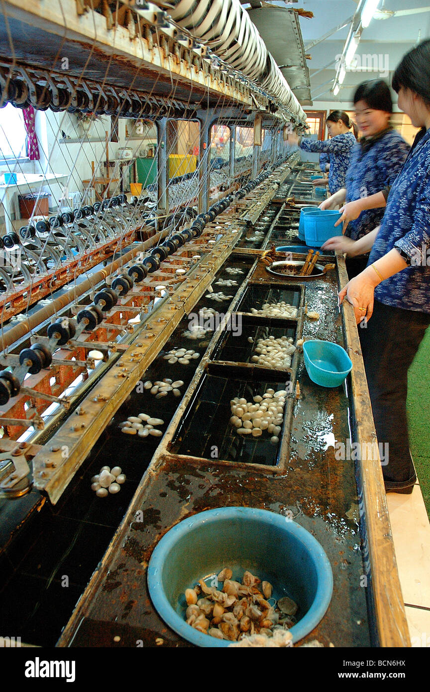 Workers harvesting silk from silk worm cacoons using machinary in a local factory, Shanghai, China Stock Photo
