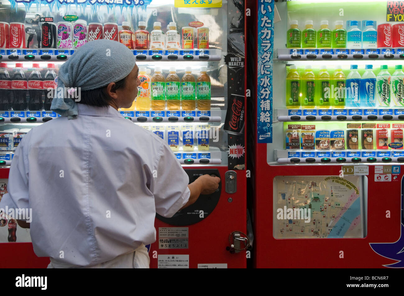 A Japanese man buying soft drink from an automatic vending machine Tokyo Japan Stock Photo