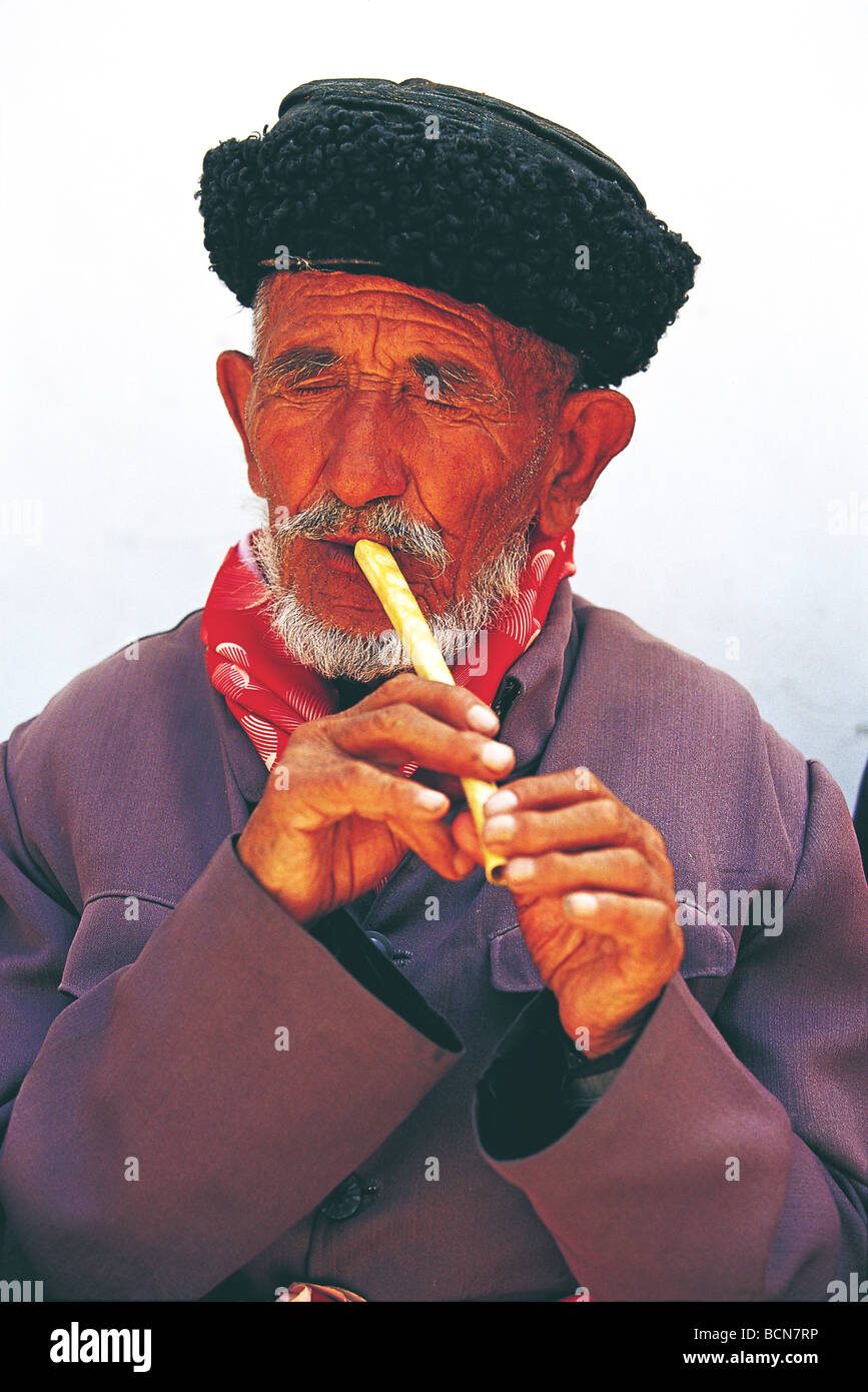 Elderly Tajik man playing music with flute made from the bone of an eagle, Taxkorgan Tajik Autonomous County, Kashgar Stock Photo