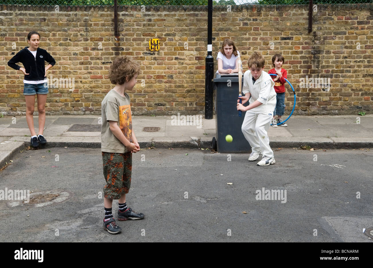 Children playing cricket in the street boy and girls. Brunswick Street Walthamstow London E17 Using the dustbin at the wicket. 2009 2000s HOMER SYKES Stock Photo