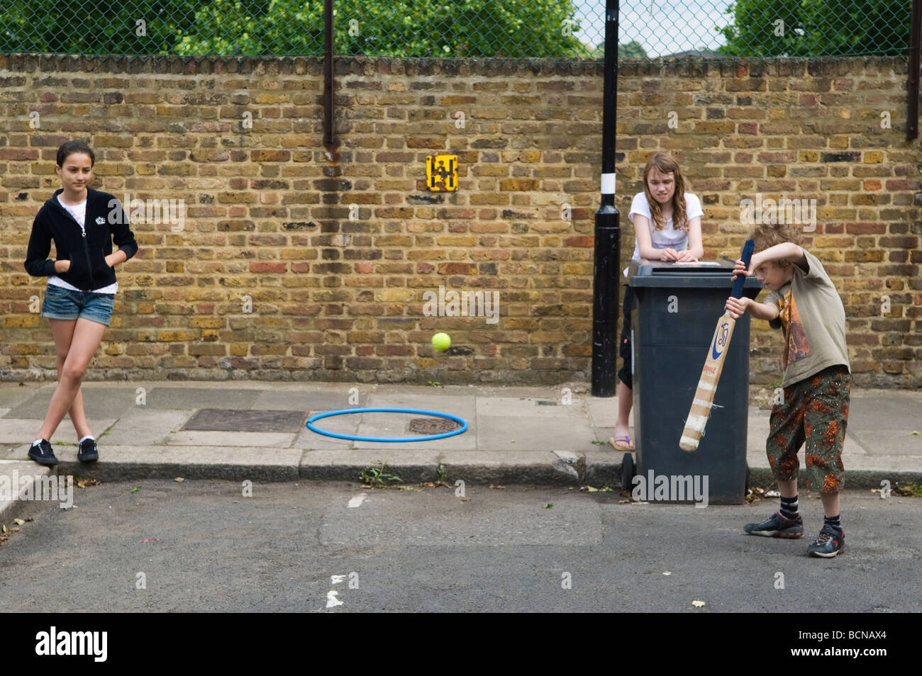 Children playing cricket in street boy girls. Brunswick Street Walthamstow London E17 Using the dustbin at the wicket. 2009 2000s England HOMER SYKES Stock Photo