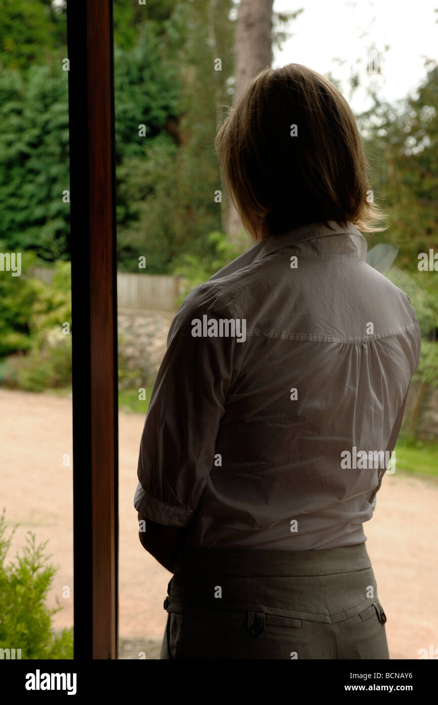 Woman standing by a window Stock Photo