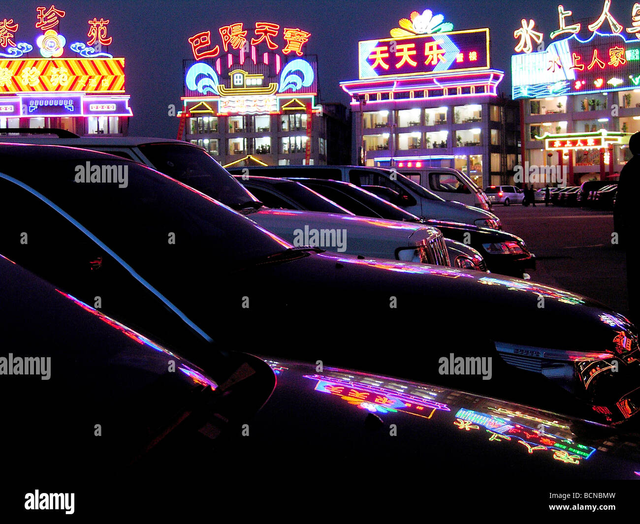 Neon lights of night clubs reflecting on the surface of gleaming luxury cars, Shanghai, China Stock Photo