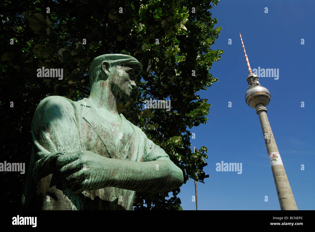 Berlin Germany Statue of a socialist worker the Fernsehturm TV tower on Alexanderplatz Stock Photo