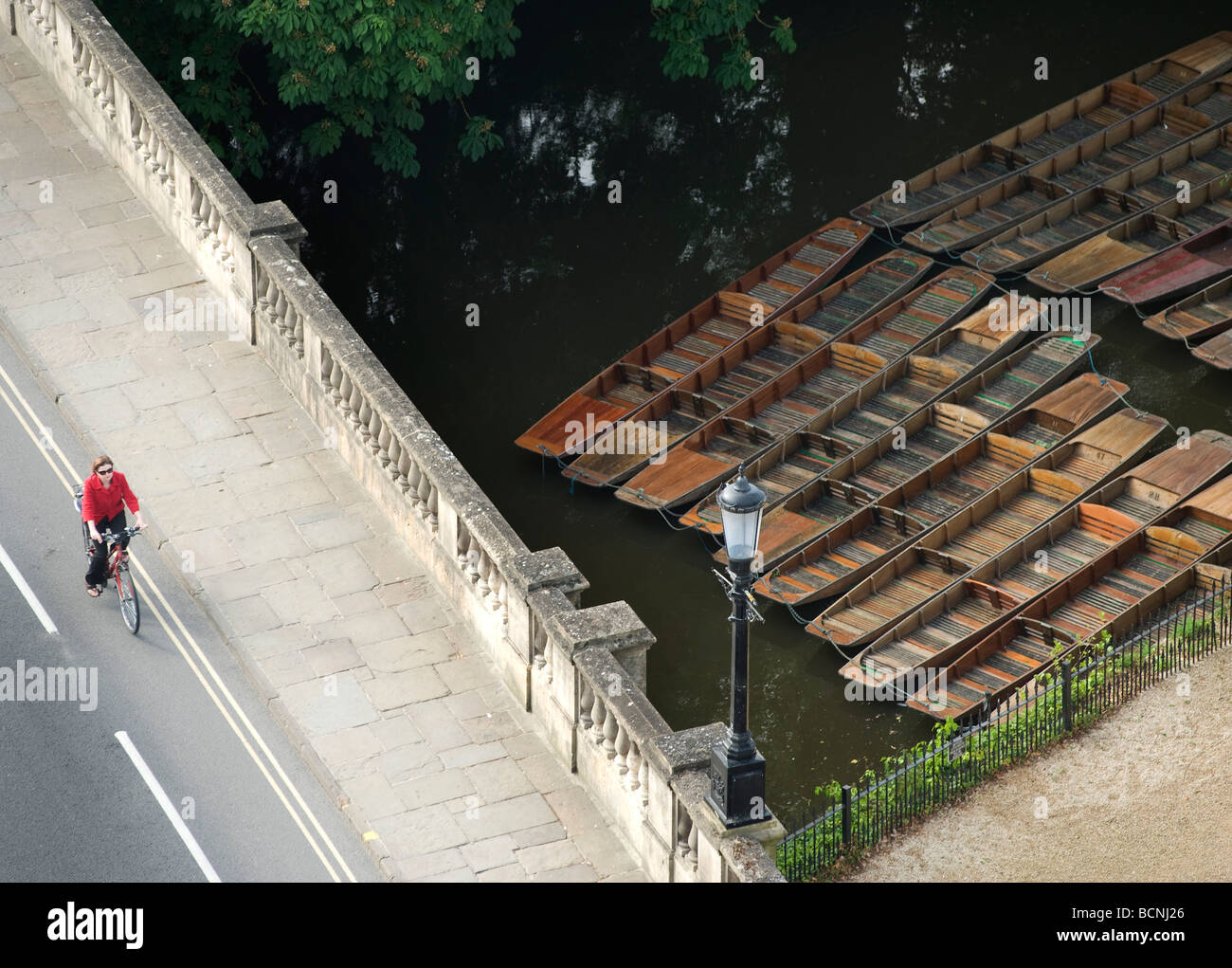 A cyclist on the way to work crosses Magdalen Bridge by the punting depot on the Cherwell in Oxford Stock Photo