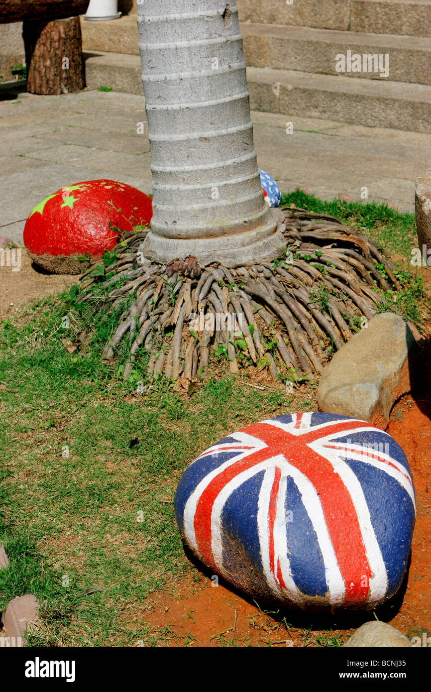 Rocks painted with national flags of different countries under a palm ...