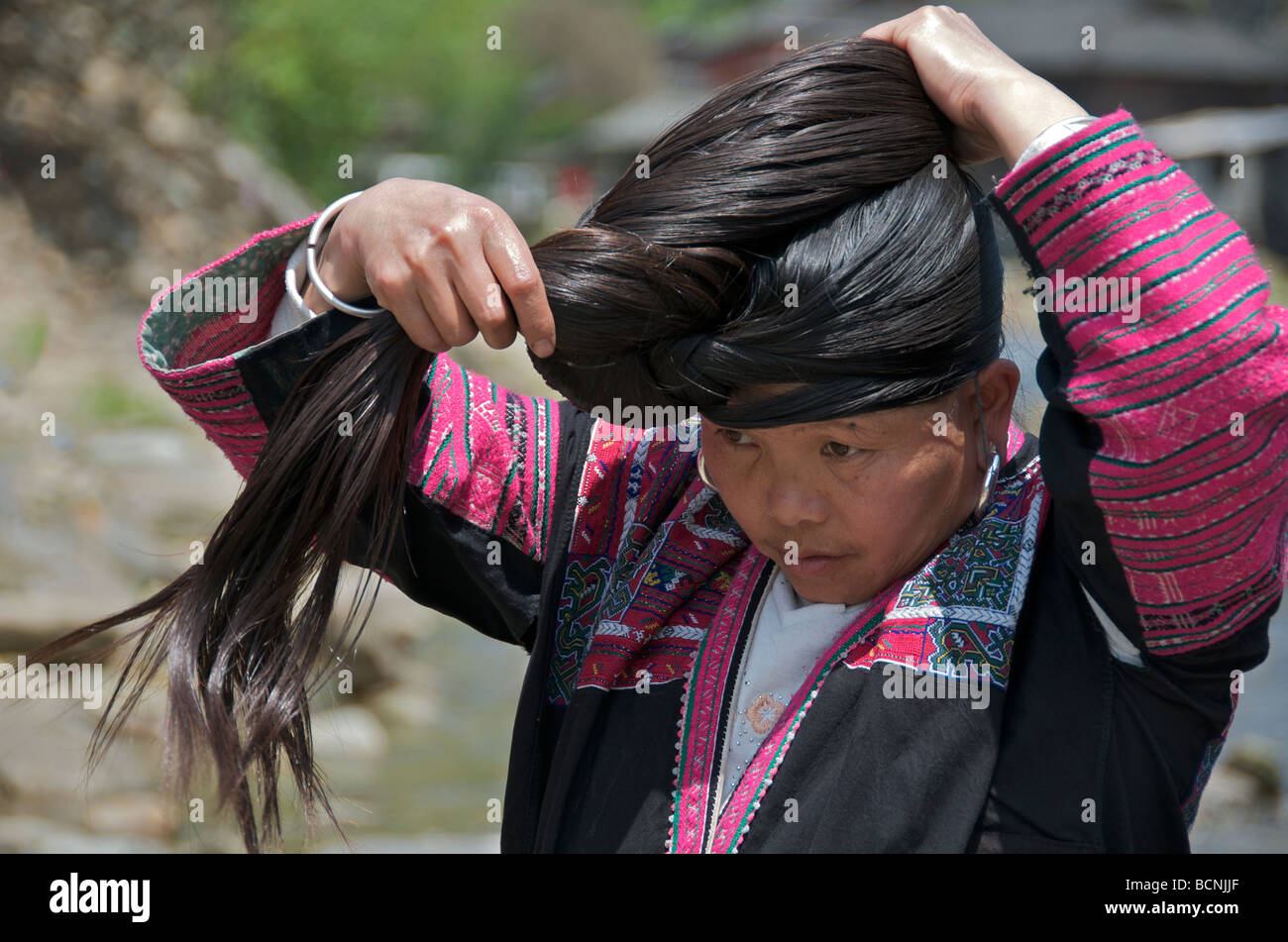 Yao Long Hair woman tying extremely long black hair beside river Huangluo  Village Guangxi China Stock Photo - Alamy