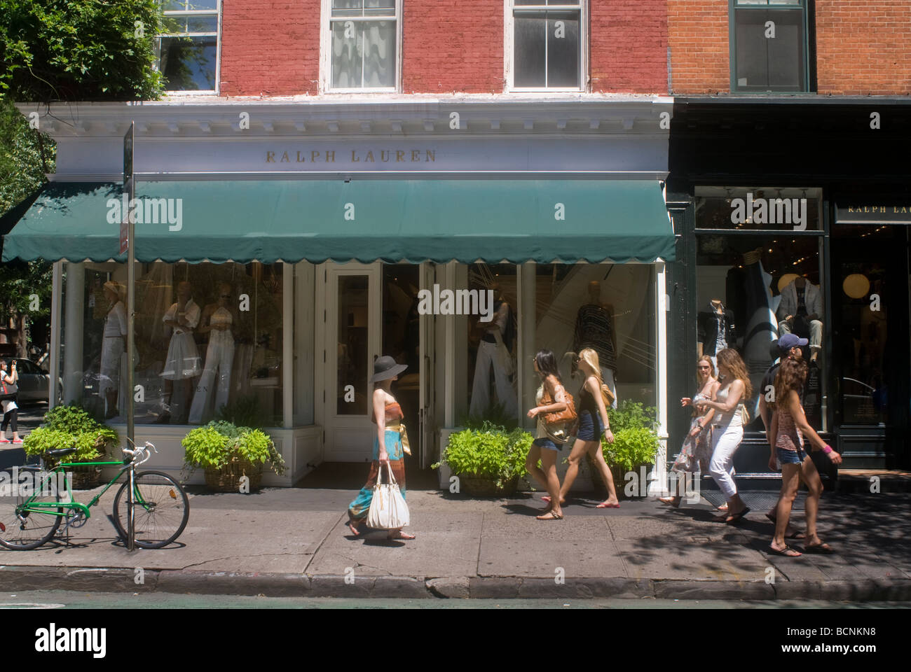 Shoppers pass upscale retail stores and businesses on Bleecker Street