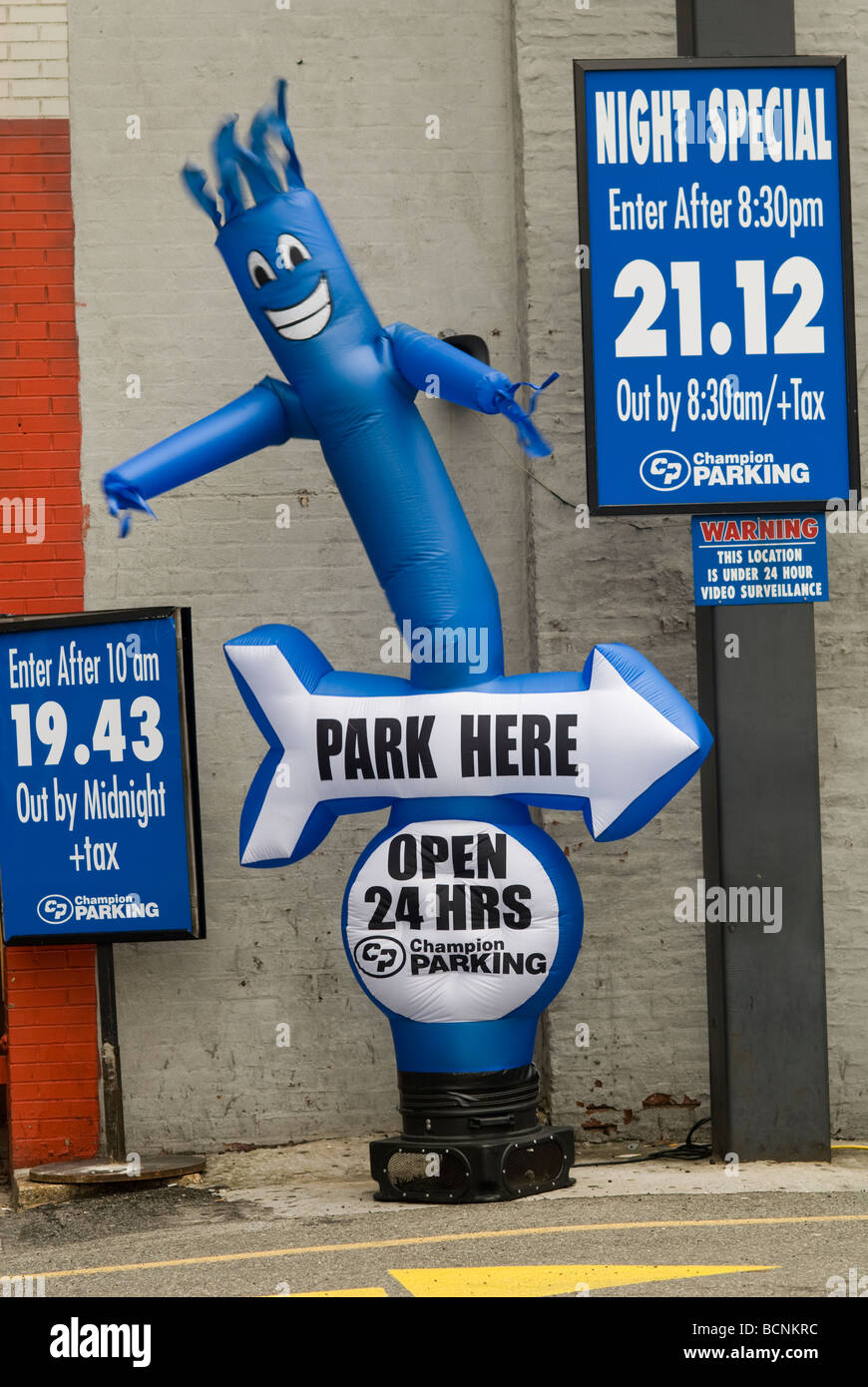 An inflatable dancing figure beckons motorists to park in a parking lot
