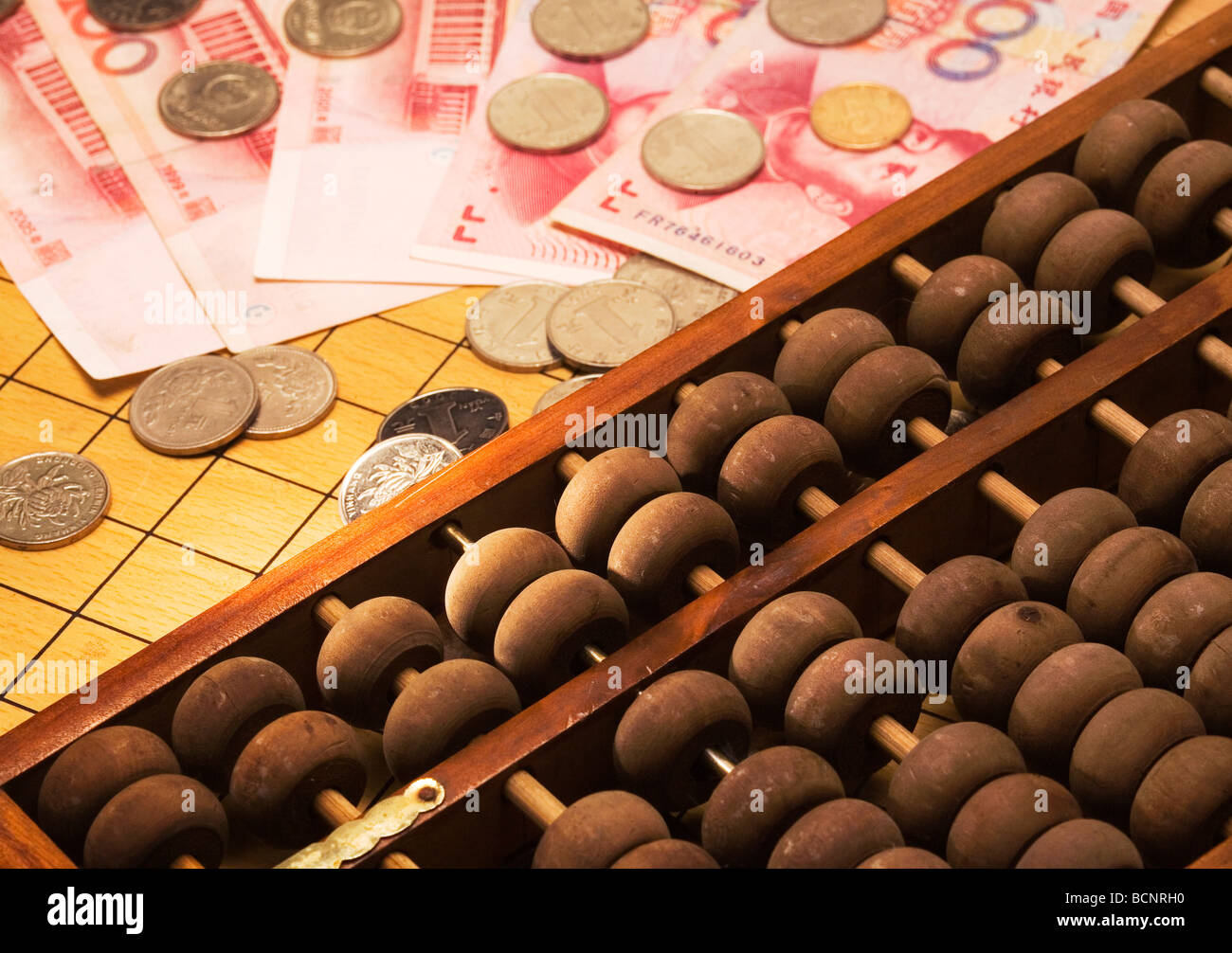 Chinese traditional calculator abacus with one hundred Chinese RMB bills and coins Stock Photo