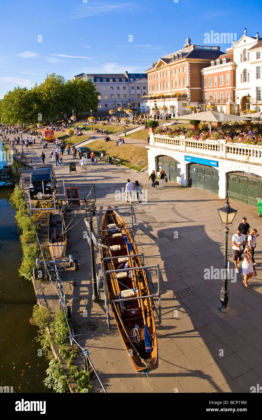 Promenading by the Thames at Richmond riverside in the summer sunshine with rowing boat up on its stand in the foreground Stock Photo