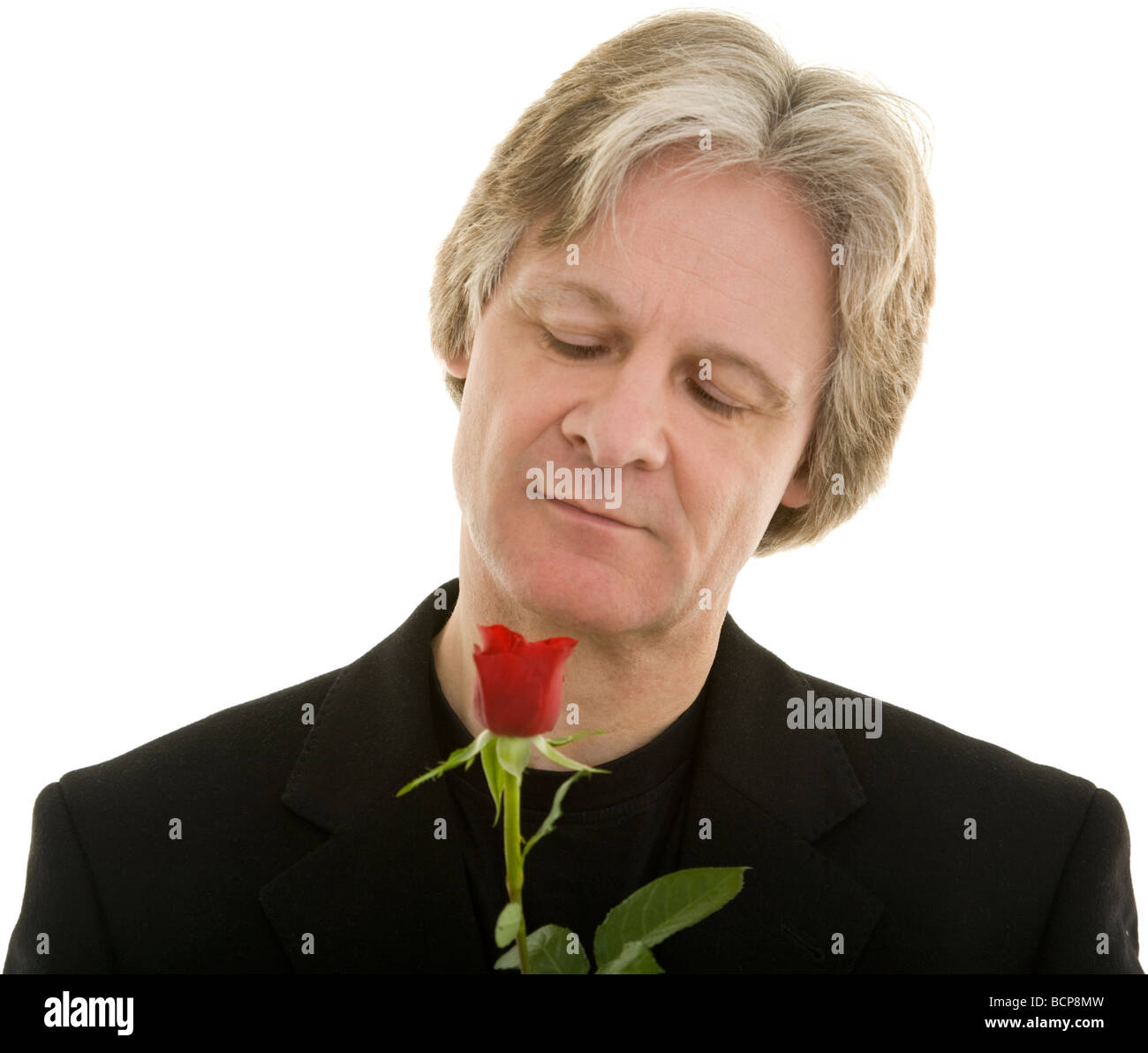 Mann schaut eine rote Rose an Stock Photo