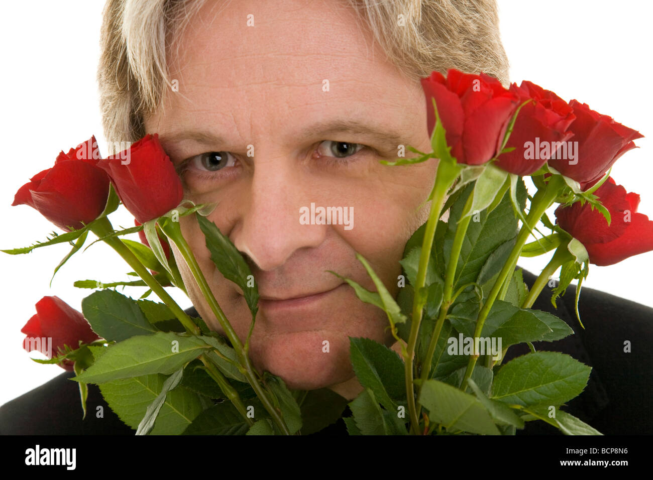 Mann schaut durch einen Strauß roter Rosen Stock Photo