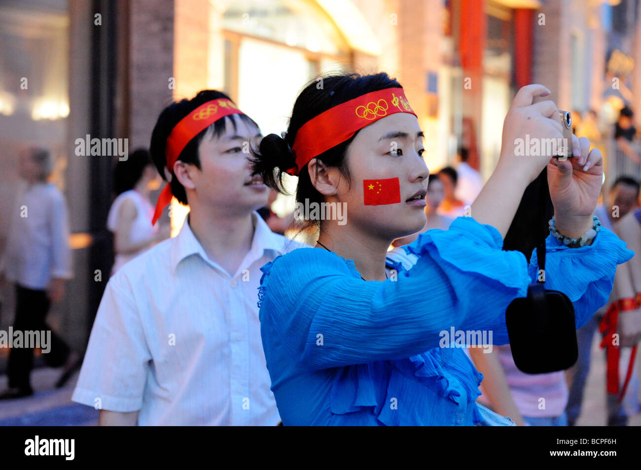 Chinese tourists with red head band and Chinese national flag stickers taking pictures when visiting Beijing during 2008 Stock Photo