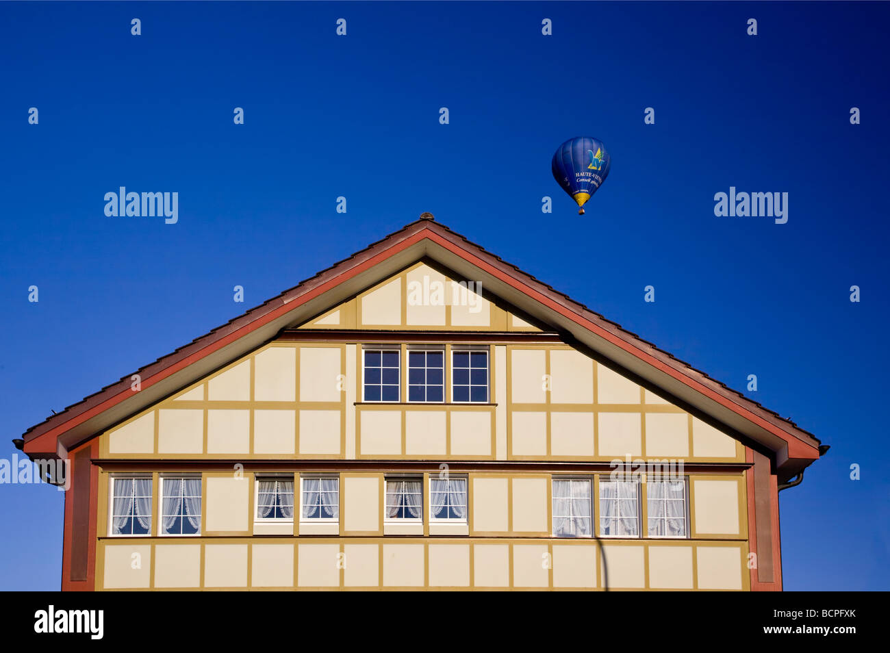 Hot air balloon taking off over traditional Appenzell house, Switzerland Stock Photo