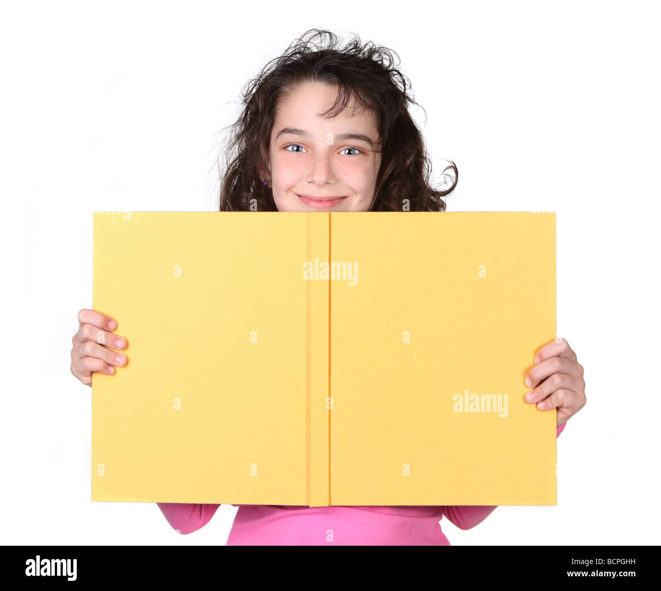 Young Girl Looking Over Her School Book With a Smile on White Background Stock Photo