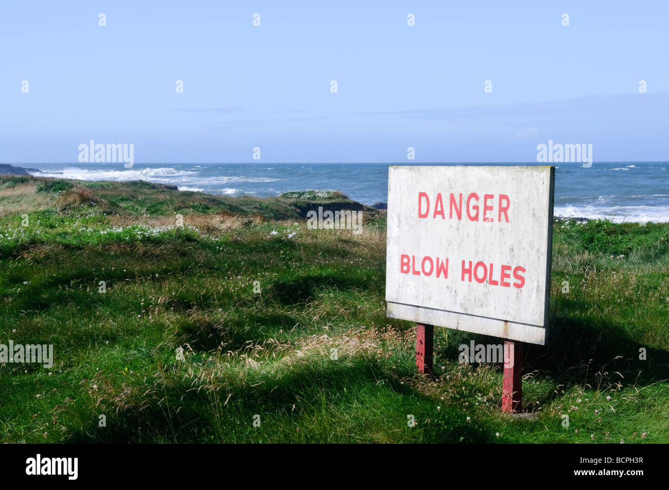 Sign warning of the presence of blow holes along coastal rocks Stock Photo