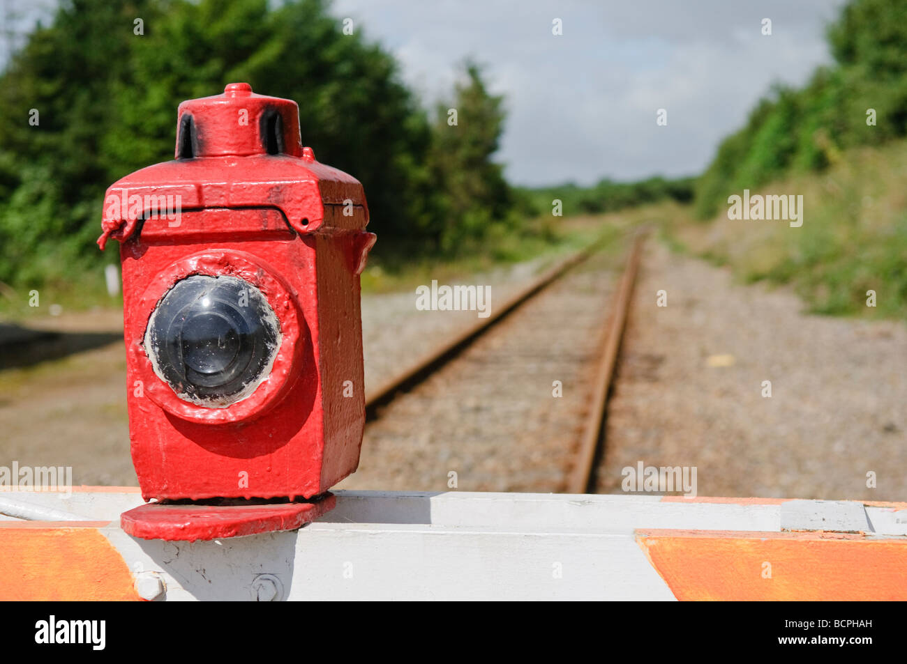 Manually operated level crossing barrier with paraffin warning lamp light across a train railway track Stock Photo