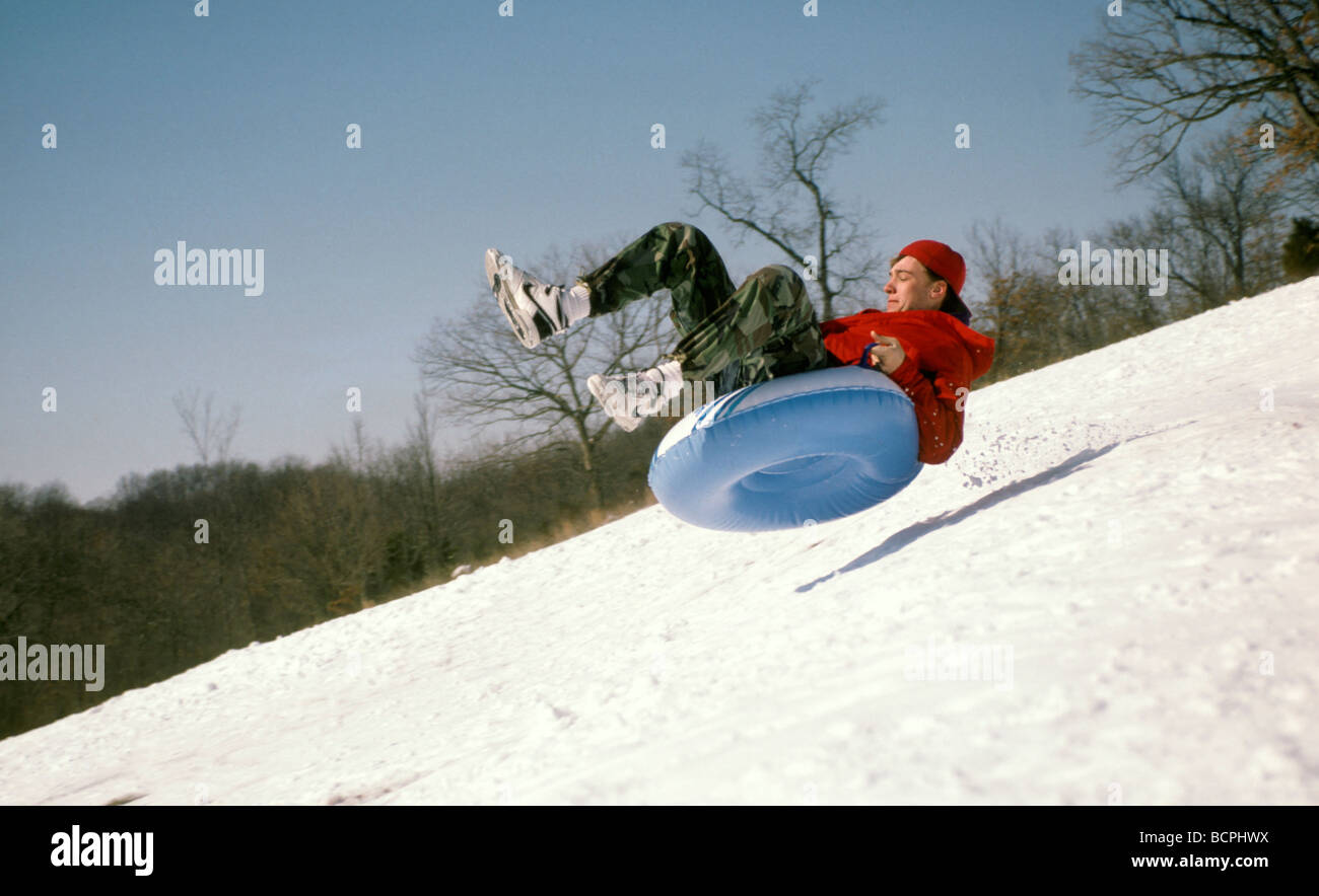 Teenager takes air: Sledding or tubing down steep hill for winter fun after snowfall. Midwest USA Stock Photo
