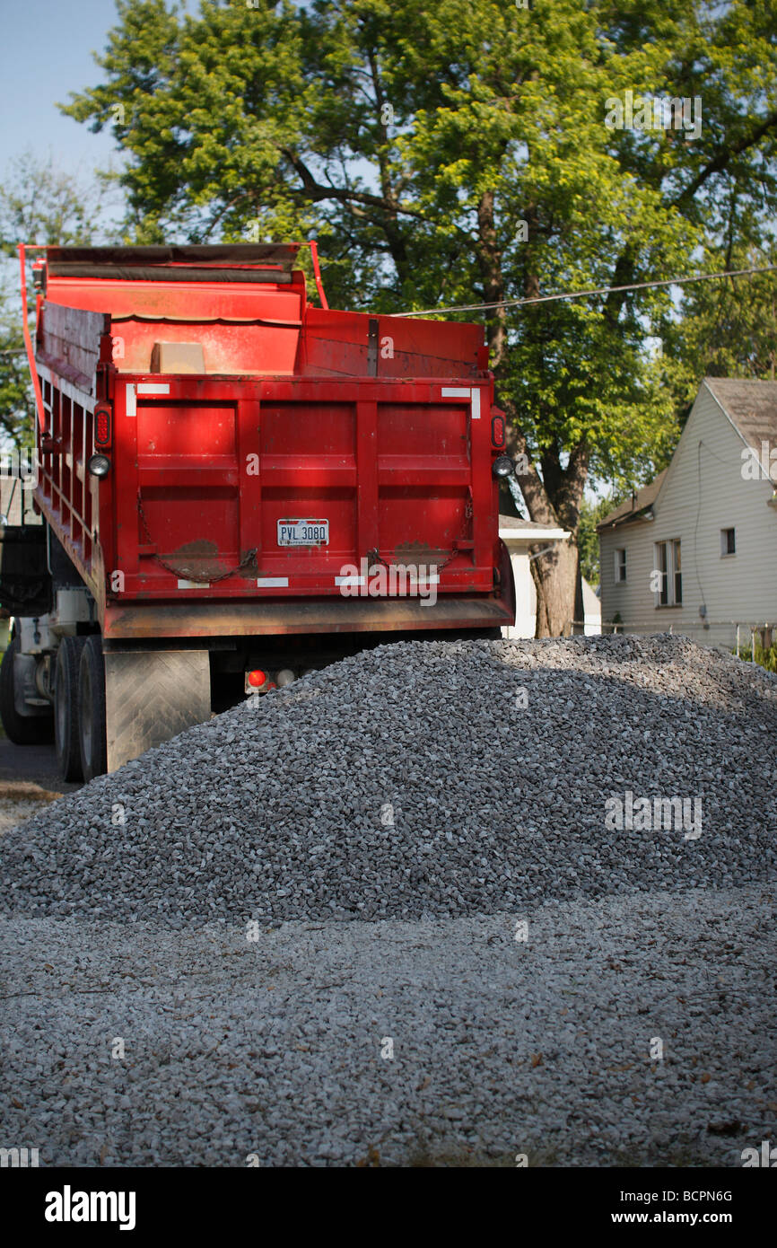 A dump truck unload unloads crushed stone on a parking lot near a house in a city a big pile of gravel  nobody none no one close up in USA hi-res Stock Photo