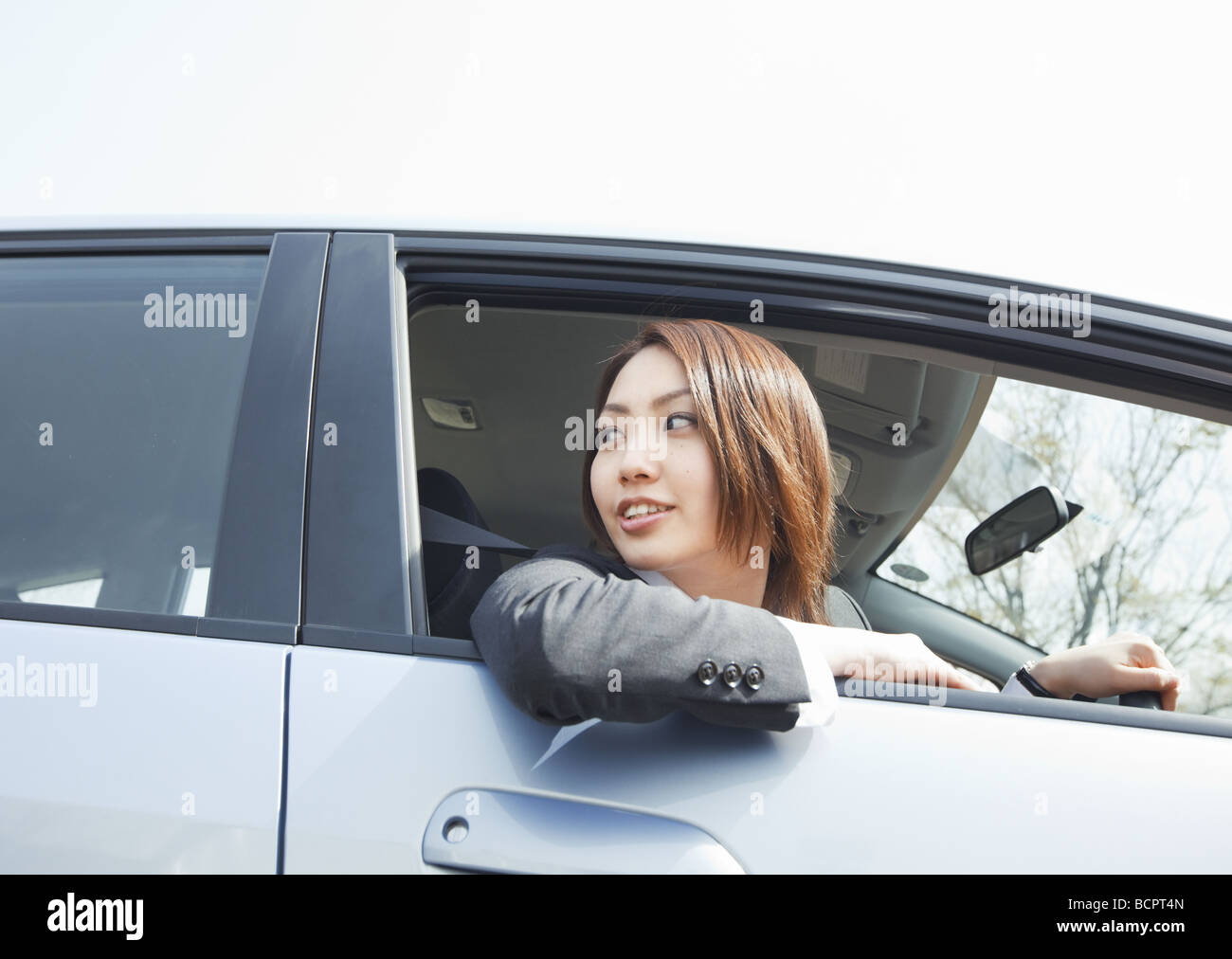 Businesswoman sticking her head out of car window Stock Photo