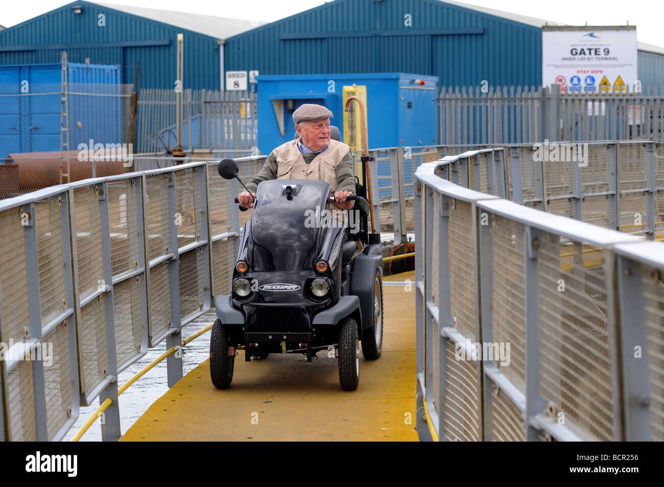 An old man on a mobility scooter crosses the lock bridge at Shoreham