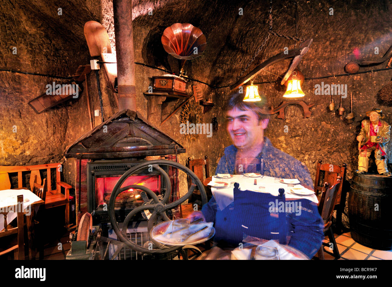 Spain, Via de la Plata: Waiter carrying plates inside of cosy Wine Cellar and cave restaurant “Bodega La Gruta” in Pobladura del Stock Photo