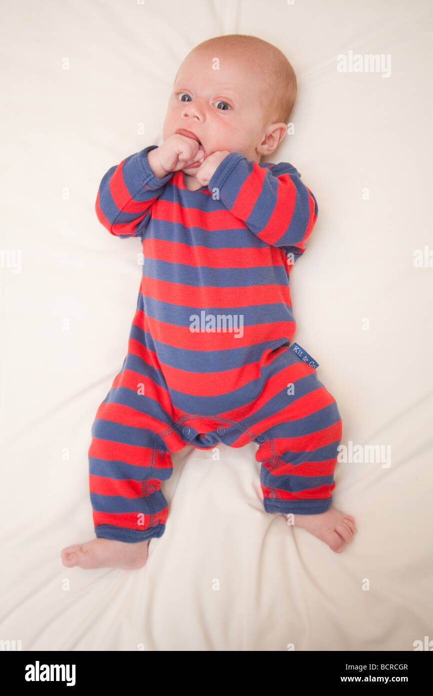 Cute baby boy chewing his hand, Dressed in stripes Stock Photo Alamy