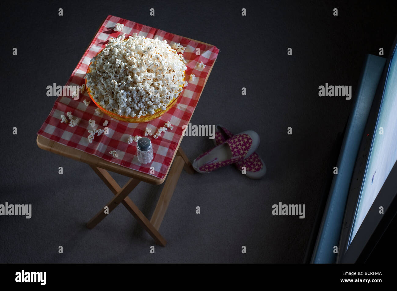 Living room of a house with popcorn on a tv tray in front of tv at night with bowl of popcorn Stock Photo